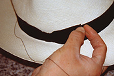 Sewing the bow on a Panama hat